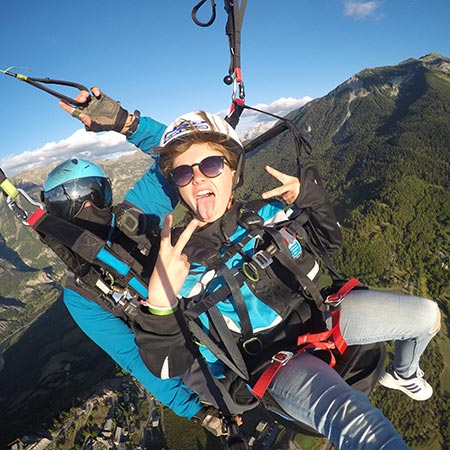 Jeune personne en vol parapente biplace manifestant sa joie.